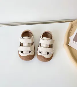 Vue détaillée de sandales pour bébé en cuir crème avec semelles en caoutchouc et velcro.