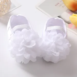 Vista dettagliata di scarpe da principessa per neonata bianche con grande fiore di stoffa