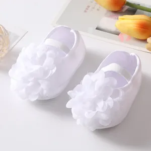 Dettaglio di scarpine da principessa bianche per neonato con grandi fiori in tessuto 3D e suole morbide
