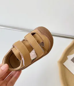 Gros plan de sandales en cuir beige pour bébé avec semelle souple pour les tout-petits.