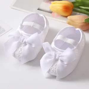 Nahaufnahme weißer Baby-Prinzessinenschuhe aus Spitze mit Schleife und weicher Sohle