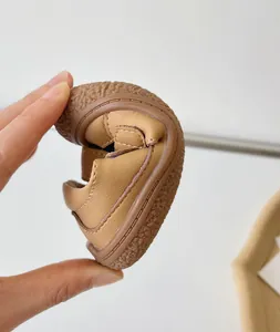 Gros plan montrant la flexibilité exceptionnelle de la sandale en cuir pour bébé.