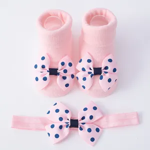 Detalle del conjunto de calcetines y diadema rosa para bebé con lazos de lunares