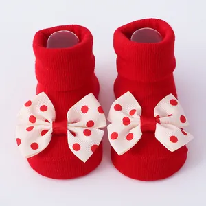 Detalle de calcetines rojos para recién nacidos con grandes lazos decorativos de lunares.