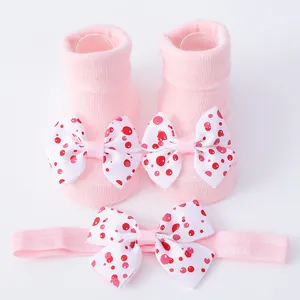 Detalle de los calcetines rosas para bebé y la diadema a juego con lazo de lunares
