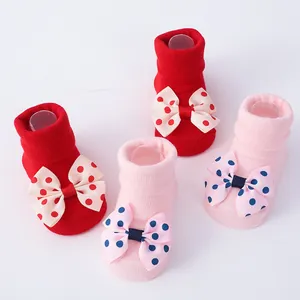 Detalle de calcetines suaves para recién nacido con lazos de lunares en rojo y rosa