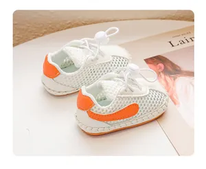 Detailaufnahme weißer Baby-Netzsandalen mit weichen orangefarbenen Akzenten und Kordelzug