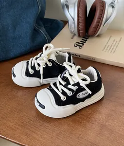 Close-up of black and white toddler canvas sneakers with soft soles on a wooden table