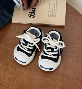 Detailed close-up of stylish black and white baby canvas walker shoes on a wooden surface.