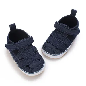 Macro view of navy blue denim baby sneakers with soft non-slip white rubber soles.