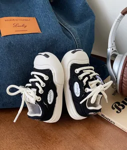 Detailed side view of black and white baby canvas sneakers featuring soft rubber soles