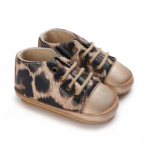 Dettaglio di scarpe da ginnastica per neonati con stampa leopardata e punte dorate lucide.