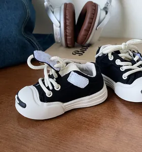 Close-up detail of black and white baby canvas sneakers with soft rubber sole on wooden table