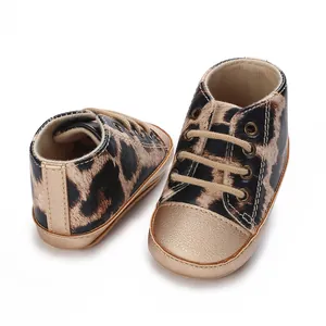 Dettaglio ravvicinato di sneaker neonati leopardate con punta dorata e lacci morbidi