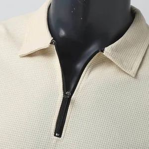 Close-up of cream waffle knit polo shirt featuring a black quarter-zip and lapel collar.
