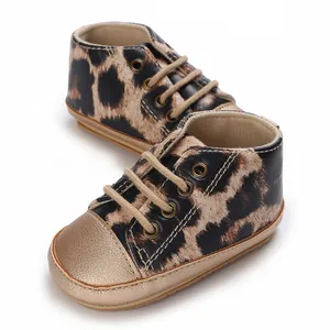 Dettaglio di sneakers neonato leopardate con suola morbida e punta oro metallico
