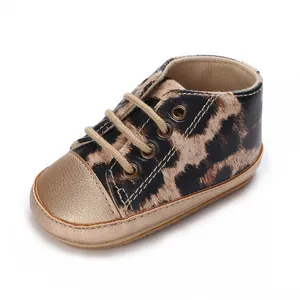 Dettaglio di scarpe primi passi leopardate per neonato con punta in oro metallizzato