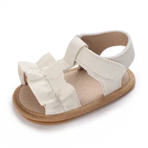 Detalle de una elegante sandalia blanca con volantes para bebé con suela flexible