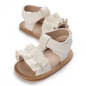 Detalle de sandalias blancas para bebé niña con volantes decorativos y suela de goma blanda
