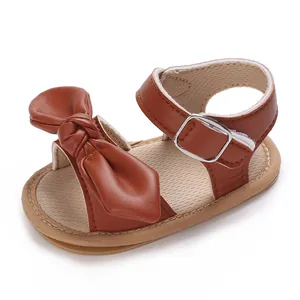 Nahaufnahme brauner Baby-Mädchen Sandalen mit großer Schleife und weicher Sohle