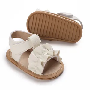 Detalle de sandalias blancas para bebé con tiras de volantes y suelas de goma blanda