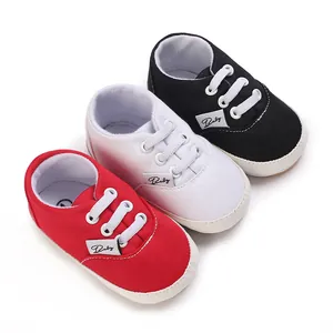 Ensemble de trois paires de chaussures de marche bébé en toile rouge, blanche et noire unie.