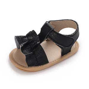 Detalle de sandalia para bebé niña con volantes negros y suela de goma suave
