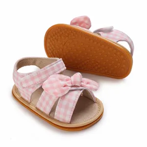 Close-up detail of pink gingham baby girl bow sandals with non-slip star pattern sole