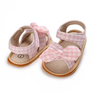 Detailed view of pink and white gingham baby girl walking shoes with a large bowknot.