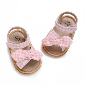 Close-up of pink and white gingham baby girl walking sandals with a large decorative bow