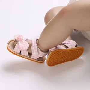 Detailed close-up view of pink checkered baby sandals with anti-slip rubber soles and bows