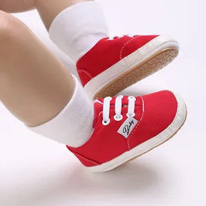 Gros plan de baskets en toile rouge pour bébé à semelle souple et lacets blancs