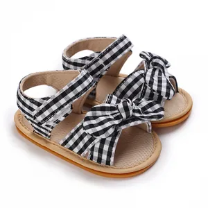 Close-up of black and white gingham baby sandals with a cute decorative bow ornament