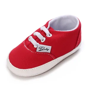 Détail d'une chaussure de marche rouge pour bébé en toile avec lacets blancs