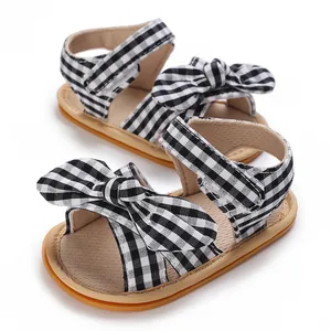Close-up detail of infant girl sandals featuring a stylish black and white checkered bow