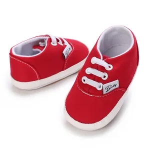 Vue détaillée de chaussures pour bébé en toile rouge avec lacets blancs et semelle souple.