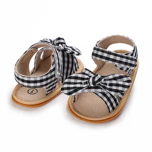 Detailed macro view of newborn girl pre-walker sandals with black gingham bow