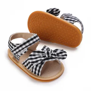Detail of baby girl's bow sandals featuring black and white gingham pattern and non-slip sole