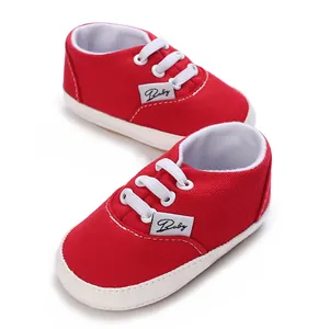 Gros plan sur des chaussures pour bébé en toile rouge avec semelles blanches souples