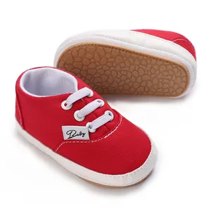 Gros plan sur chaussures bébé en toile rouge avec semelles souples blanches