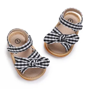 Macro view of newborn girl walker shoes featuring decorative bow and gingham pattern
