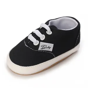 Gros plan détaillé d'une chaussure de marche pour bébé en toile noire à lacets blancs.