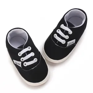 Vue détaillée de chaussures de bébé en toile noire avec semelles blanches souples
