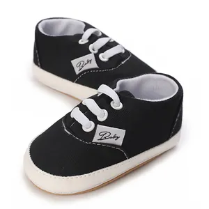 Baskets classiques en toile noire pour bébé avec lacets blancs et semelles souples.