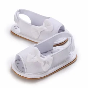 Nahaufnahme von weißen, atmungsaktiven Baby-Sandalen mit Schleife und weicher Sohle