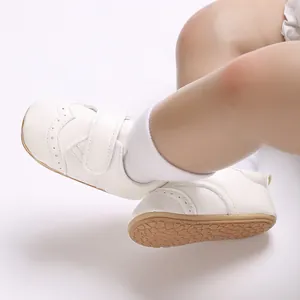 Close-up of white baby walking shoes with anti-slip rubber soles and velcro straps.