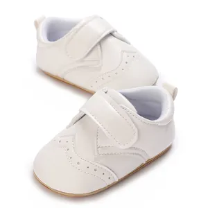 Close-up view of white faux leather baby shoes featuring decorative perforations and a secure strap.