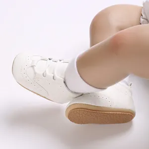 Close-up view of white baby soft-sole sneakers with a textured anti-slip rubber bottom.
