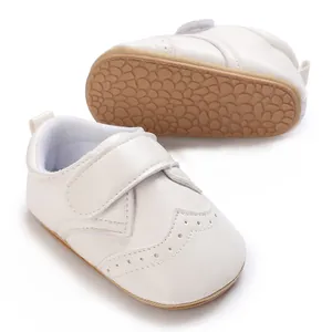 Close-up of elegant white infant leather shoes showing non-slip rubber sole texture details
