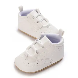 Detailed view of white soft sole baby sneakers with litchi grain leather and brogue design.
